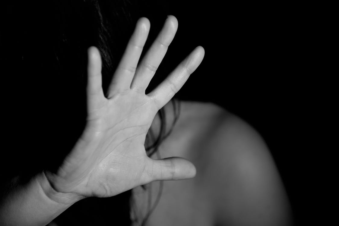 person in dark room shileding their face with their hand