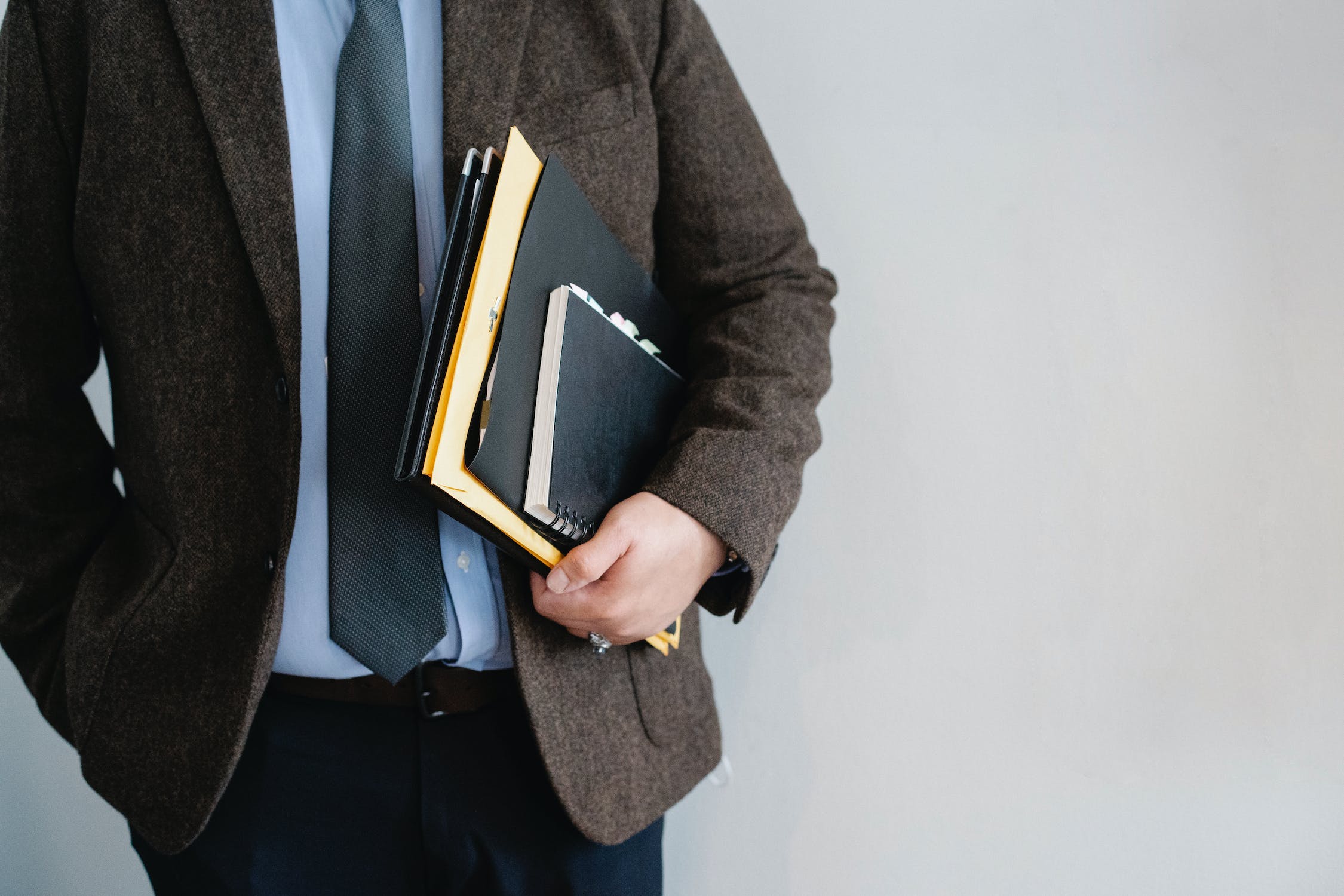 man's torso in a suit and tie with files under his arm